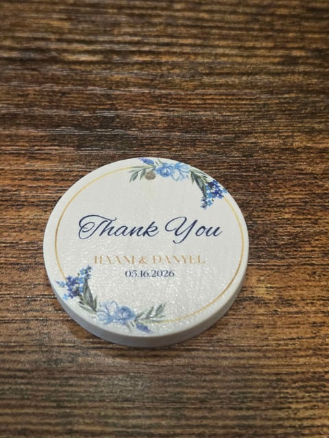 Round white wedding favor sticker with blue floral design, Thank You text, and names Hailey & Danyel with date 05.16.2026
