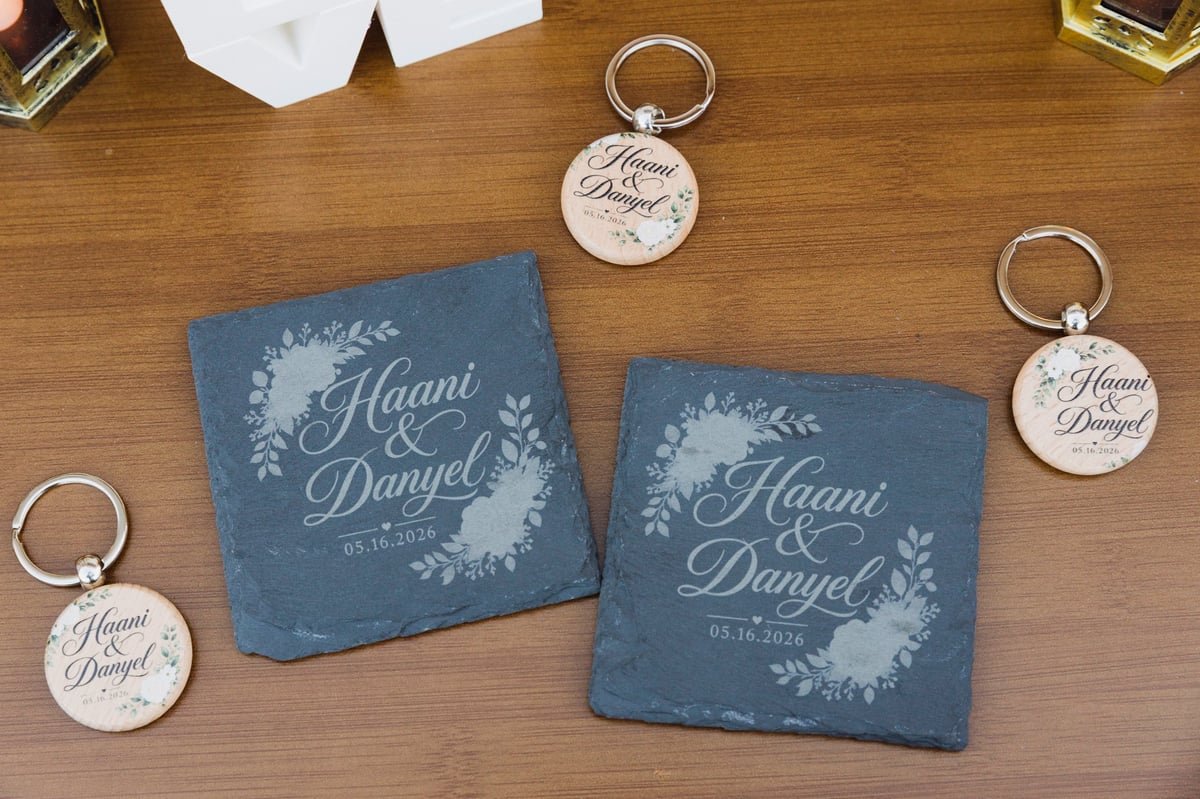 Personalized engraved keychains and coasters with Haani Danyel names and floral designs on wooden surface